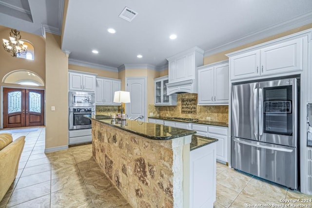 kitchen with dark stone countertops, white cabinetry, appliances with stainless steel finishes, and backsplash