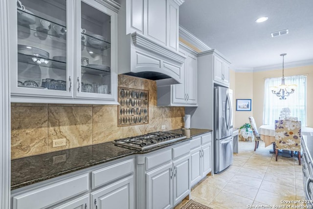 kitchen with appliances with stainless steel finishes, premium range hood, hanging light fixtures, decorative backsplash, and white cabinets