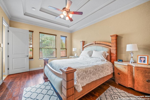 bedroom with crown molding, dark hardwood / wood-style flooring, ceiling fan, and a raised ceiling