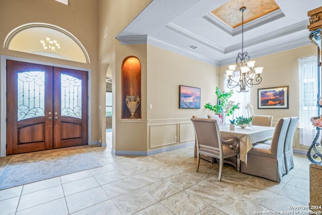 dining room featuring an inviting chandelier, a raised ceiling, and ornamental molding