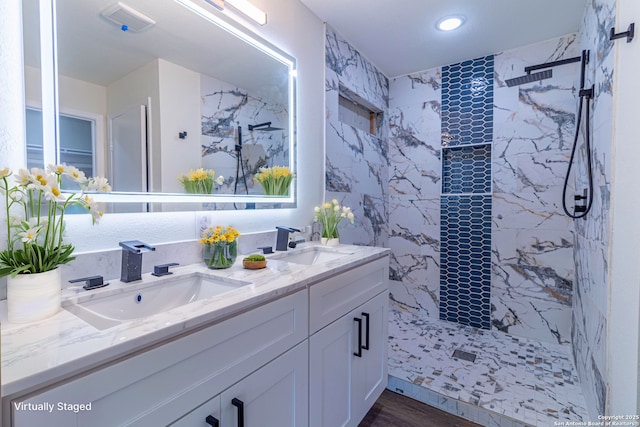 bathroom with wood-type flooring, tiled shower, and vanity