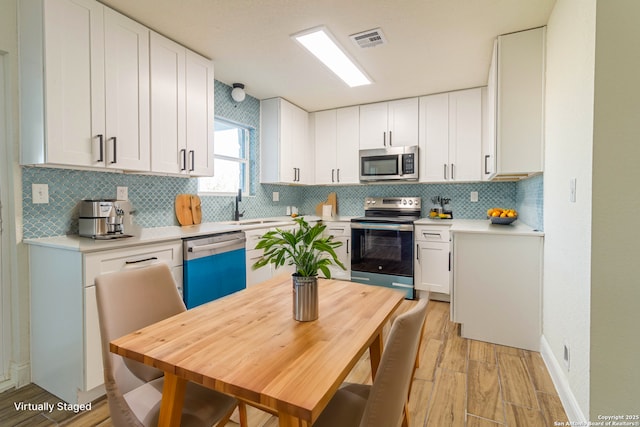 kitchen featuring white cabinets, appliances with stainless steel finishes, tasteful backsplash, and sink