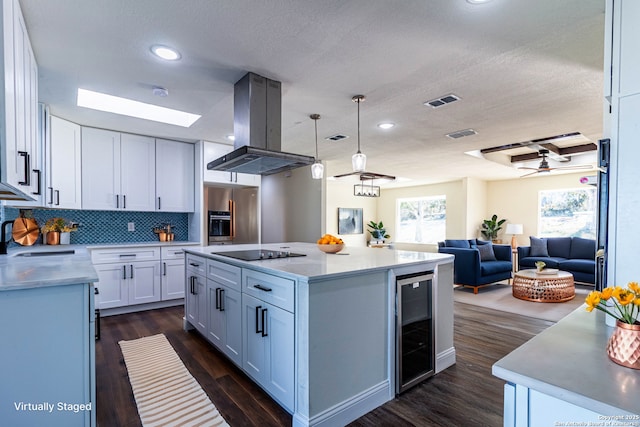 kitchen with white cabinets, a center island, island range hood, and wine cooler