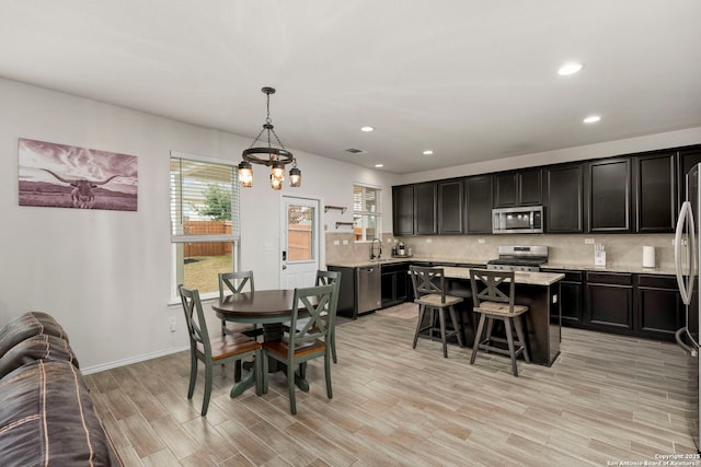 dining room with light wood-type flooring, a notable chandelier, and sink