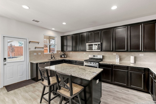 kitchen featuring a center island, light stone countertops, appliances with stainless steel finishes, sink, and backsplash