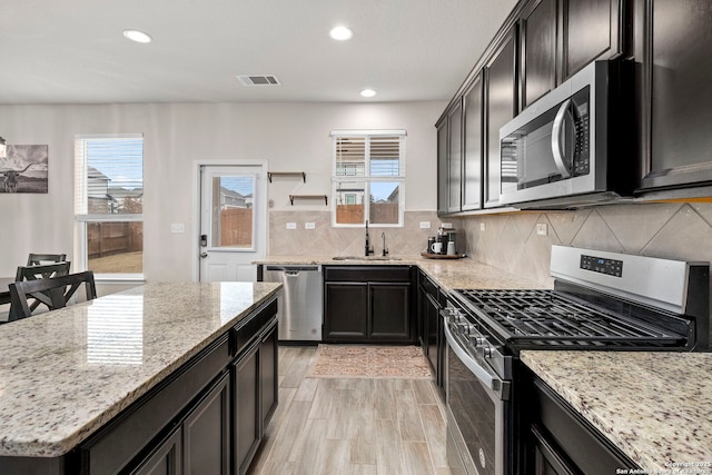 kitchen featuring light stone counters, sink, a wealth of natural light, and appliances with stainless steel finishes