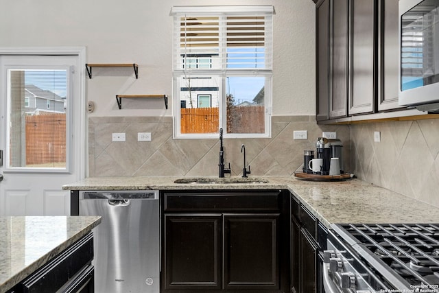 kitchen featuring sink, backsplash, light stone countertops, and appliances with stainless steel finishes