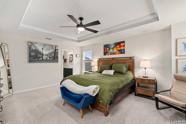 carpeted bedroom with ensuite bath, ceiling fan, and a raised ceiling