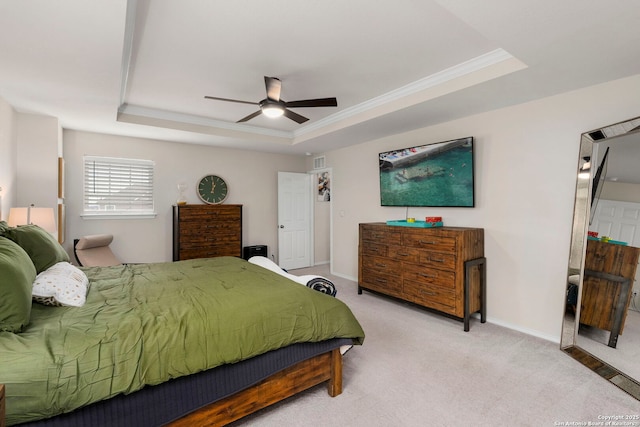 bedroom with ornamental molding, light colored carpet, ceiling fan, and a raised ceiling