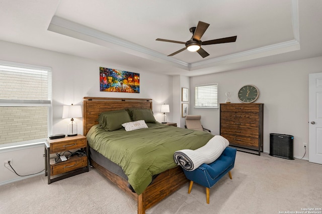 carpeted bedroom with ceiling fan, a tray ceiling, and crown molding