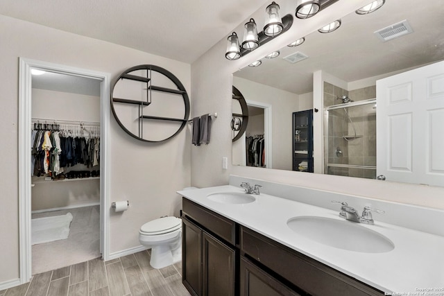 bathroom with toilet, a shower with shower door, and vanity