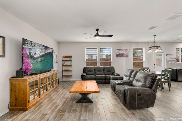 living room featuring ceiling fan with notable chandelier