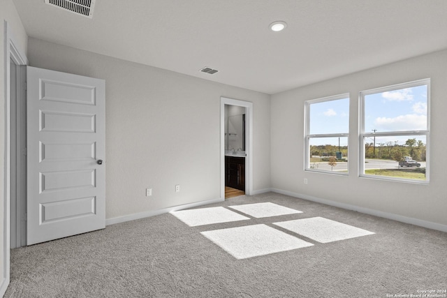 unfurnished bedroom with light colored carpet and ensuite bathroom