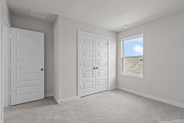 unfurnished bedroom featuring a closet and light colored carpet