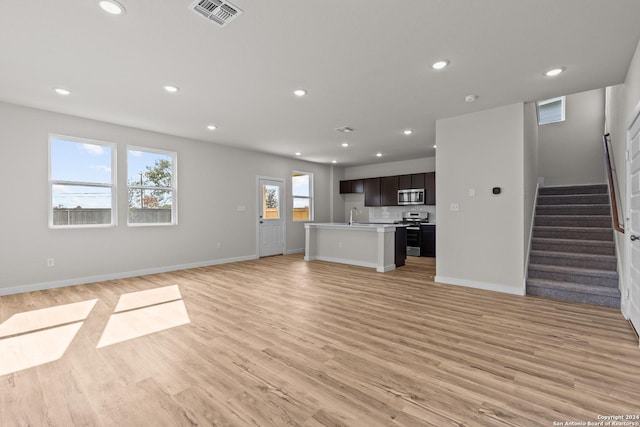 unfurnished living room with sink and light hardwood / wood-style flooring