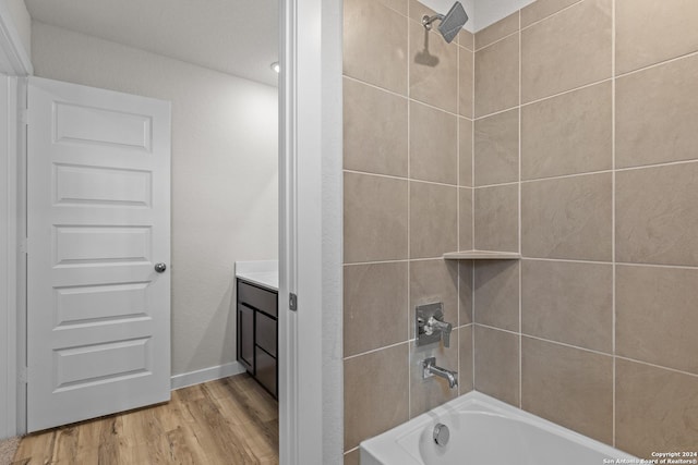 bathroom with tiled shower / bath combo, hardwood / wood-style flooring, and vanity