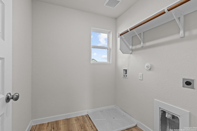 clothes washing area featuring hardwood / wood-style flooring, hookup for a washing machine, hookup for an electric dryer, and hookup for a gas dryer