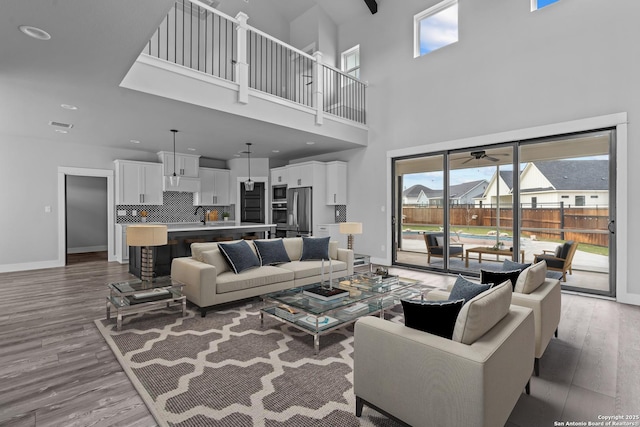 living room featuring hardwood / wood-style floors, a towering ceiling, and ceiling fan