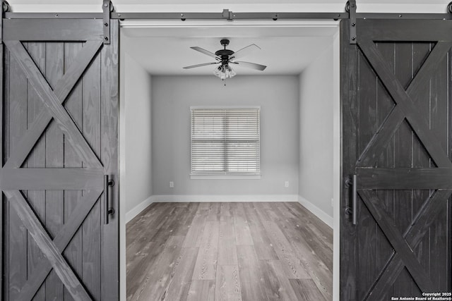 foyer entrance featuring hardwood / wood-style floors, ceiling fan, and a barn door