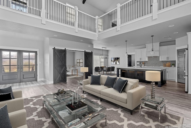 living room with hardwood / wood-style flooring, a high ceiling, french doors, and a barn door