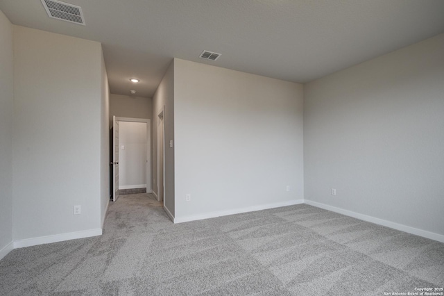 spare room with carpet floors, visible vents, and baseboards