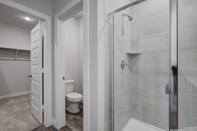 full bath with baseboards, a shower stall, toilet, and a spacious closet