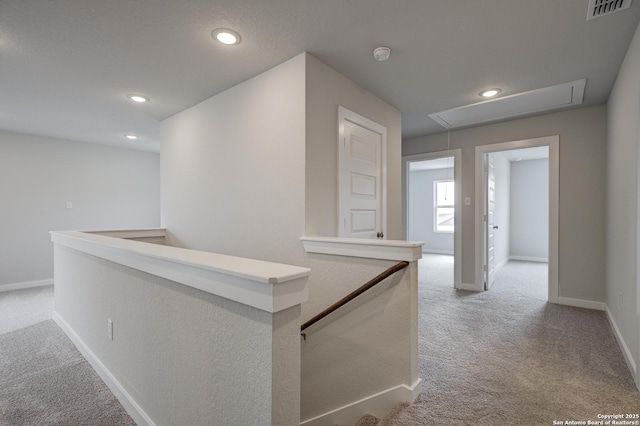 hall featuring visible vents, carpet flooring, an upstairs landing, and attic access