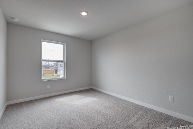 spare room featuring carpet floors and baseboards