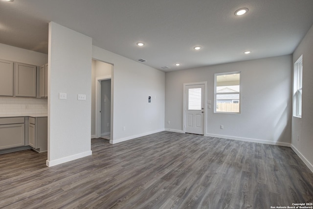 unfurnished living room featuring dark wood-type flooring, recessed lighting, visible vents, and baseboards