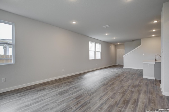 unfurnished room with baseboards, dark wood finished floors, a sink, and recessed lighting