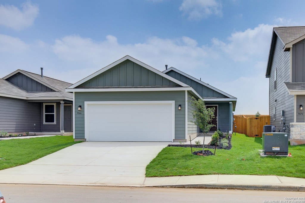 view of front facade with a garage, a front lawn, and central air condition unit