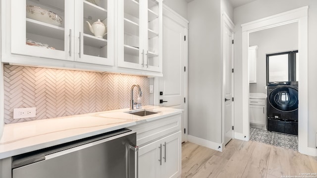 interior space with light stone countertops, dishwasher, decorative backsplash, sink, and white cabinets