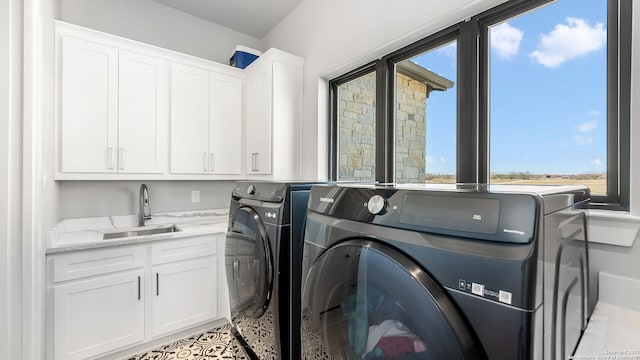 clothes washing area with sink, washer and clothes dryer, and cabinets