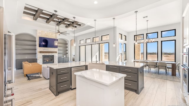 kitchen with a fireplace, appliances with stainless steel finishes, built in features, and a kitchen island