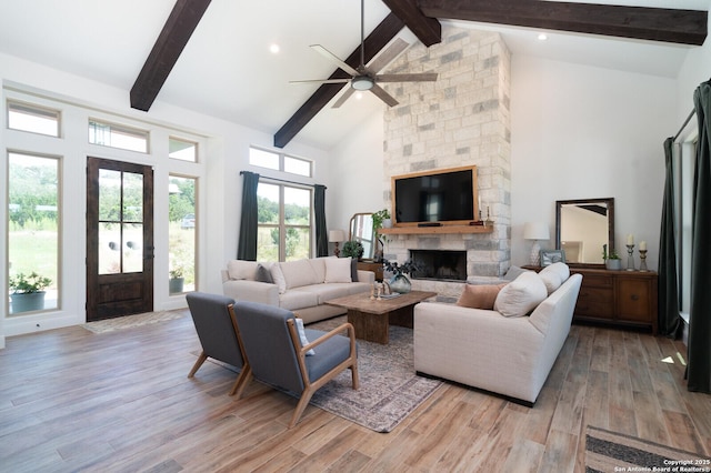 living room featuring a fireplace, light hardwood / wood-style floors, beam ceiling, and high vaulted ceiling