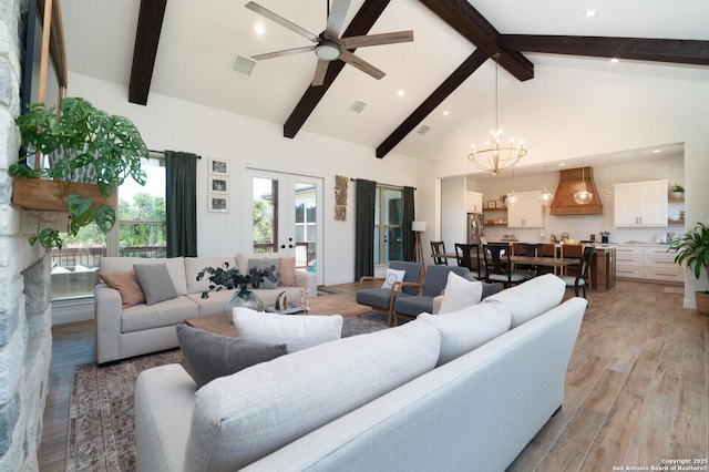 living room featuring beamed ceiling, light wood-type flooring, french doors, high vaulted ceiling, and ceiling fan with notable chandelier