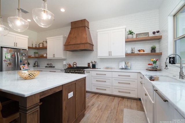 kitchen with premium range hood, white cabinetry, stainless steel fridge, and tasteful backsplash