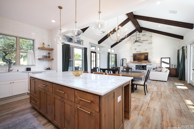 kitchen with pendant lighting, light hardwood / wood-style flooring, sink, a fireplace, and a center island