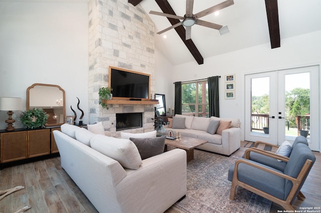 living room featuring beamed ceiling, hardwood / wood-style floors, a fireplace, french doors, and high vaulted ceiling