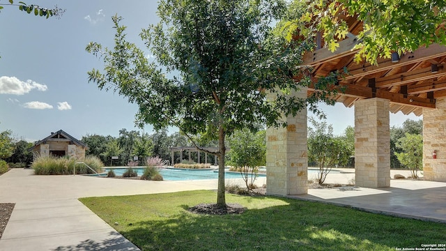 exterior space featuring an outdoor structure, a lawn, a swimming pool, and a patio