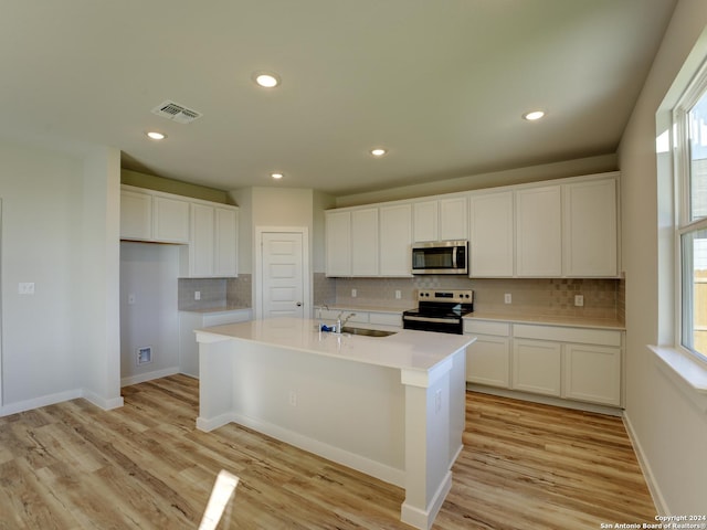 kitchen featuring range with electric stovetop, sink, white cabinets, a center island with sink, and light hardwood / wood-style floors