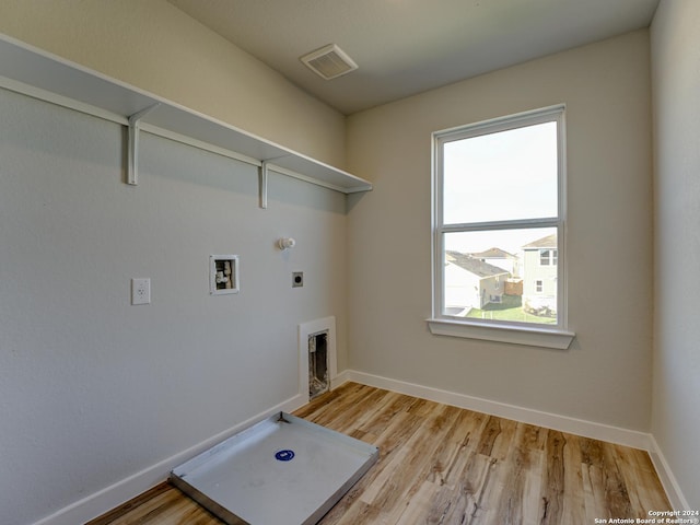 laundry room featuring hookup for a washing machine, a wealth of natural light, light hardwood / wood-style flooring, and electric dryer hookup