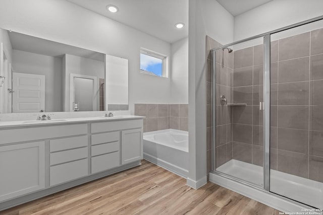 bathroom featuring hardwood / wood-style flooring, plus walk in shower, and vanity