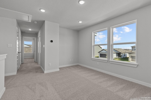 carpeted empty room with a healthy amount of sunlight and a textured ceiling