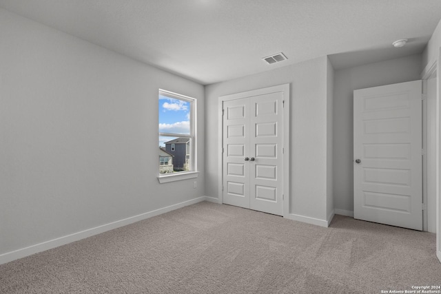 unfurnished bedroom featuring a closet and light carpet