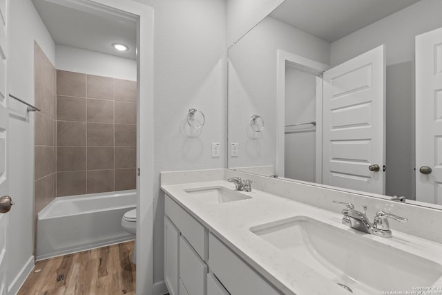 full bathroom featuring vanity, toilet, tiled shower / bath combo, and hardwood / wood-style floors