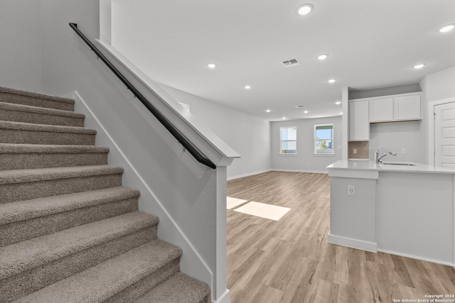 staircase featuring hardwood / wood-style floors and sink