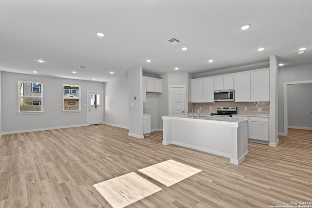 kitchen with backsplash, appliances with stainless steel finishes, a center island with sink, and white cabinets