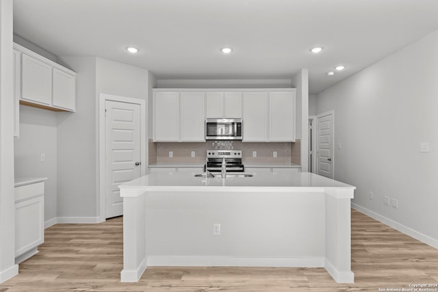 kitchen with white cabinetry, appliances with stainless steel finishes, a kitchen island with sink, and sink