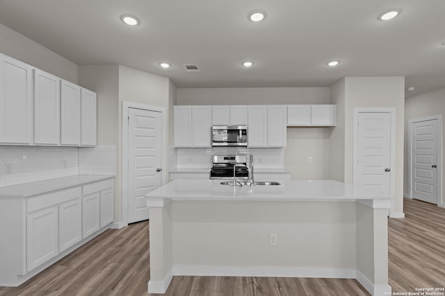 kitchen featuring white cabinetry, a kitchen island with sink, light hardwood / wood-style floors, and appliances with stainless steel finishes